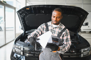 Car service, repair, maintenance concept,auto mechanic man writing to the clipboard at workshop,...