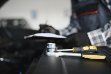 Engineer expertly examines car motor using advanced mechanical tools, ensuring optimal automotive performance and safety. African american garage employee conducts annual vehicle checkup