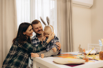 Mum and Dad put rabbit ears on their son. A cheerful atmosphere at Easter