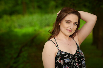 Naklejka premium Stunning young woman in short sundress poses on grassy path