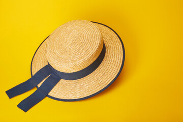 Classic gondolier straw hat with blue ribbons isolated on the bright solid fond plain yellow background