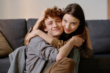 Medium close up portrait of young adult Caucasian couple hugging and posing for photo