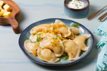 Dumplings with mashed potatoes filling. Varenyky, vareniki, pierogi, pyrohy - dumplings with filling on blue plate on green blue wood background