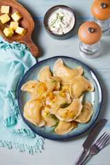 Dumplings with mashed potatoes filling. Varenyky, vareniki, pierogi, pyrohy - dumplings with filling on blue plate on green blue wood background. High angle view