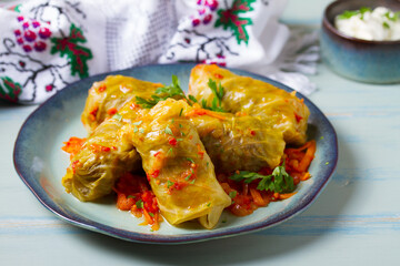 Stuffed cabbage leaves. Cabbage wraps or rolls. Chou farci, dolma, sarma, golubtsy or golabki on blue plate on green blue table