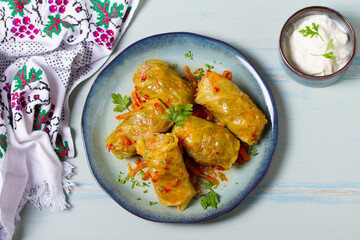 Stuffed cabbage leaves. Cabbage wraps or rolls. Chou farci, dolma, sarma, golubtsy or golabki on blue plate on green blue table. High angle view