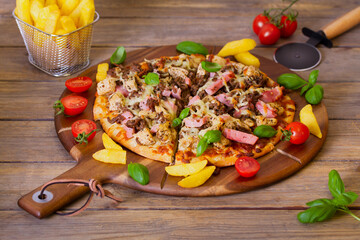 Delicious beef chicken and ham pizza on wood pizza serving plate with chips and fizzy drinks