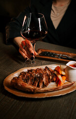 Delicious grilled meat served with sauce and a glass of red wine in an intimate dining setting