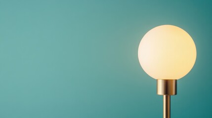 A modern lamp with a round bulb stands against a teal wall, creating a minimalist and serene ambiance.