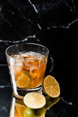 whiskey in a glass with ice and lime on a black mirror background, place for drinks, alcohol, alcoholic cocktails, exquisite whiskey cocktail