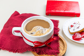 cappuccino in a large white cup with a red ribbon, gingerbread cookies with white glaze, red heart-shaped lollipops on a red napkin, Valentine's Day, Valentine's Day gift, festive composition, flatlay