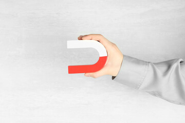 Woman with horseshoe magnet on light background, closeup