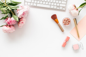 Female workspace with computer and peony flowers, top view