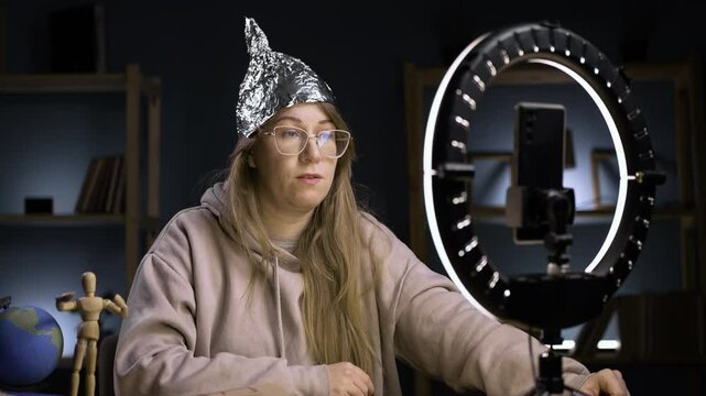 Strange crazy vlogger with cellphone, paranoid woman streaming at home conspiracy theory broadcasting in vlog, with shocked amazed face. blogging and conspiracy theory