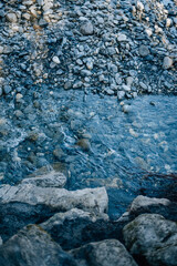 Sea rocky bottom under transparent blue water. Clear turquise lake surface rippled with sun ray reflection.