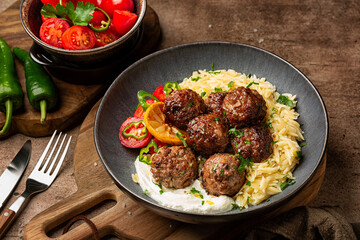 Greek Delicious beef meatballs -  Keftedes, or cutlets, made with origano, mint and lemon, served with orzo or risoni pasta and vegetables. Homemade food.