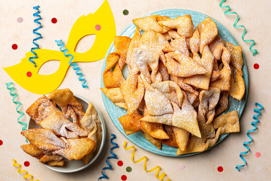 Top view of Angel wings or bugnes, bugie, or chvorost; faworki. Traditional  Europian carnival sweet crisp pastry, deep-fried and sprinkled with powdered sugar. Decorated table.