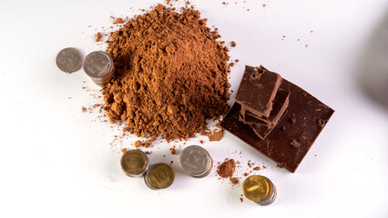 A pile of chocolate and coins on a white background. The coins are scattered around the chocolate,...