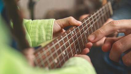 Fototapeta premium Playing a musical instrument. Father teaching daughter to play electric guitar. Close up