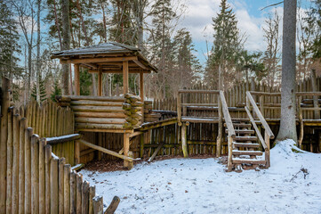 Wooden fortress wall against the forest. Wooden installation in the style of an ancient city. Stockade fence made of logs. Kartavkalna Nature Trail, Latvia.