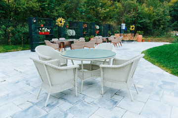 Outdoor wicker furniture with glass table in a scenic and tranquil garden setting