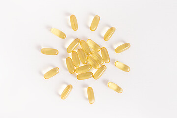Yellow vitamin capsules are laid out in the shape of sun on white background. Vitamin D