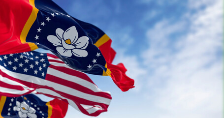 Mississippi state flags waving with the American flag on a clear day