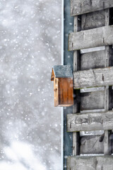 A birdhouse is sitting on a wooden fence in the snow