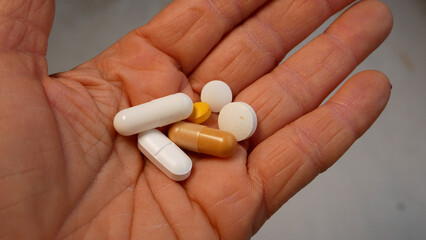 A woman's hand holds tablets on an open palm - round and in capsules. The concept of treatment, the prescription of treatment by the doctor, pills. Self-medication, use of dietary supplements.