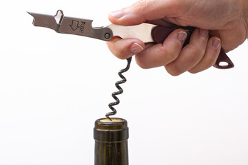 Woman's hand opening a bottle of wine with a manual corkscrew