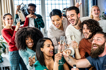 Diverse young people toasting and drinking sparkling wine - Group of happy friends enjoying dancing...