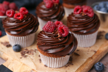 Tasty cupcakes with chocolate cream and berries on brown table, closeup