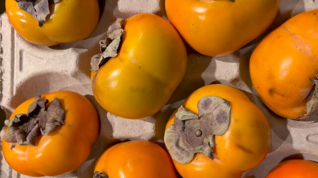 Persimmon apple sharon arranged on cardboard crate. Tracking shot in top view on persimmon for sale at grocery store