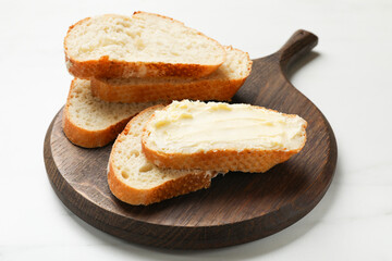 Fresh bread with butter on white table, closeup