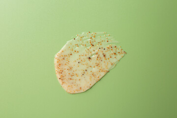 Smear of body scrub on green background, top view