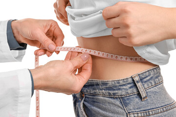 Weight loss. Nutritionist measuring patient's waist with tape on white background, closeup