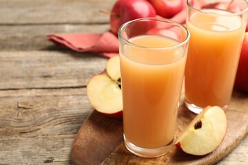 Tasty apple juice in glasses and fresh fruits on wooden table, closeup