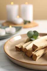 Palo santo sticks and eucalyptus leaves on white wooden table, closeup