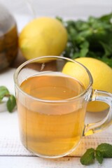 Aromatic mint tea with lemons and fresh leaves on white wooden table, closeup