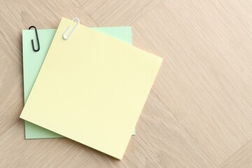 Paper notes with clips on wooden table, top view. Space for text