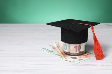 Tuition payment. Graduate hat and euro banknotes on light wooden table. Space for text