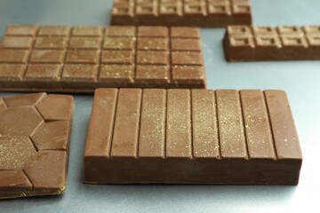 Different tasty Dubai chocolate bars with pistachios and knafeh on grey table, closeup