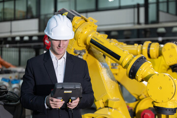 Caucasian engineer inspecting robotic arms in a manufacturing facility