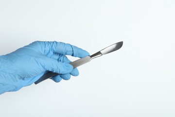 Doctor with surgical scalpel on white background, closeup. Space for text