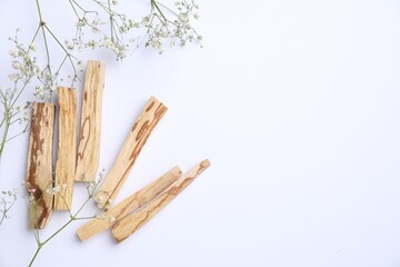 Palo santo sticks and gypsophila flowers on white background, flat lay. Space for text