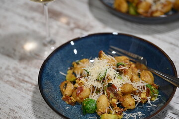 A close-up view of homemade gnocchi served on a blue plate, topped with freshly grated cheese
