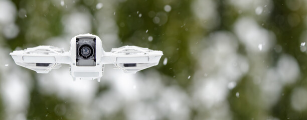 A white drone with a camera on it flying through the snow