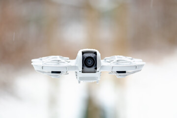 A white drone with a camera on it is flying in the air