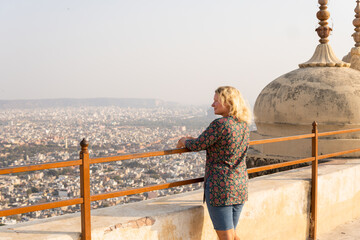 Young blonde woman discovering Rajasthani architecture on hot sunny day in Jaipur, India