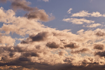 The sunlight gently touches the edges of the snow-white clouds.